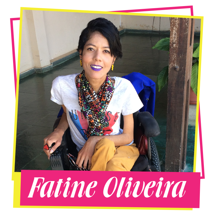 Fatine está sorrindo e sentada em sua cadeira de rodas. Ela está usando blusa branca com detalhes em azul e rosa, um cachecol verde com vermelho e calças amarelas. Fatine usa batom roxo.