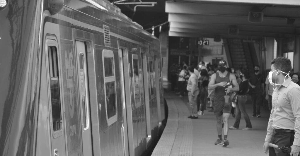 Pessoas esperam o metrô de máscara