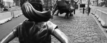 escultura de garota em frente a touro na frente do prédio de Wall Street