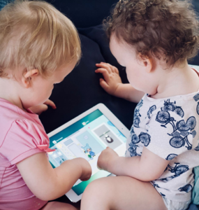 Dois bebês brincam em tablet