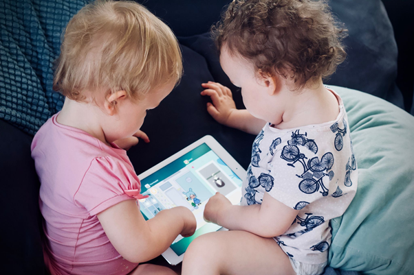Dois bebês brincam em tablet