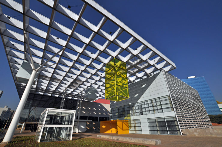 Fotografia do prédio atual da Empresa Mineira de Comunicação. Prédio branco com pequeno design amarelo no teto.