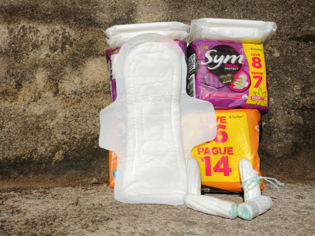 Pacotes de absorventes íntimos escorados em um muro, e absorventes abertos.