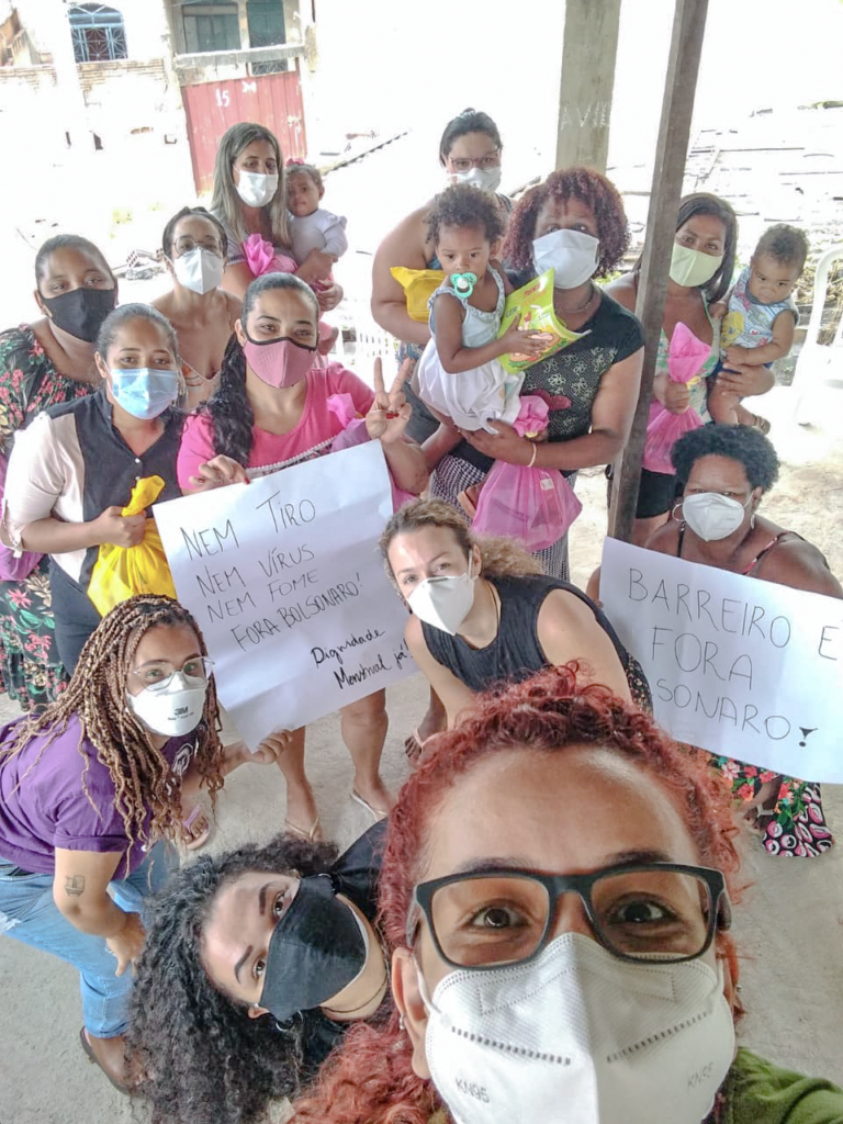 Mulheres do grupo "Flores de Resistência" reunidas e segurando cartazes pedindo pela dignidade menstrual e pelo “Fora Bolsonaro”.
