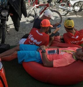 Entregadores de ifood deitados em puff vermelho em uma praça