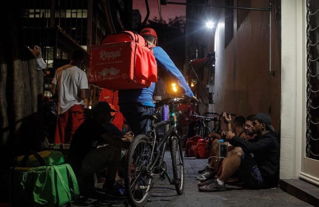 Entregador de ifood carrega bicicleta em rua