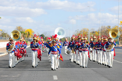 Imagem de desfile do exército brasileiro. Soldados vestem azul e branco e tocam instrumentos.