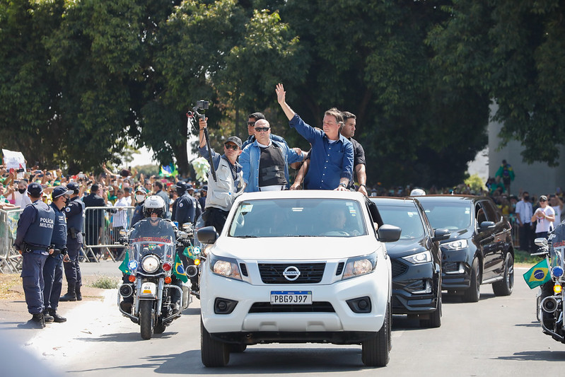 foto de Bolsonaro em teto solar de carro acenando para o público