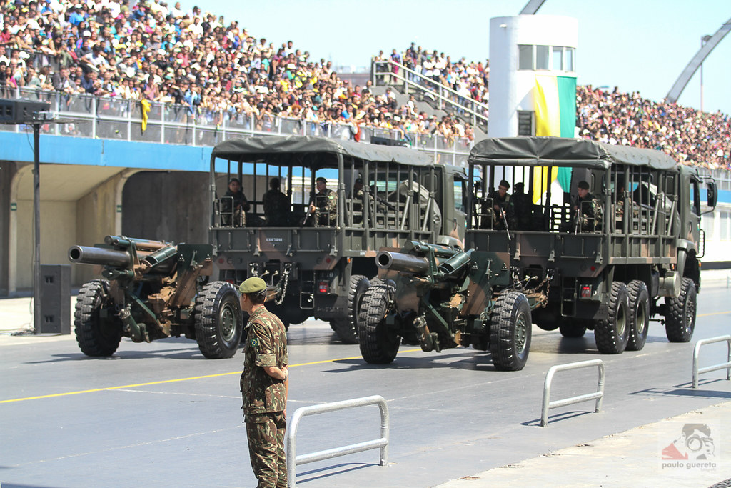 foto de desfile militar mostrando soldado em primeiro plano e carros militares ao fundo