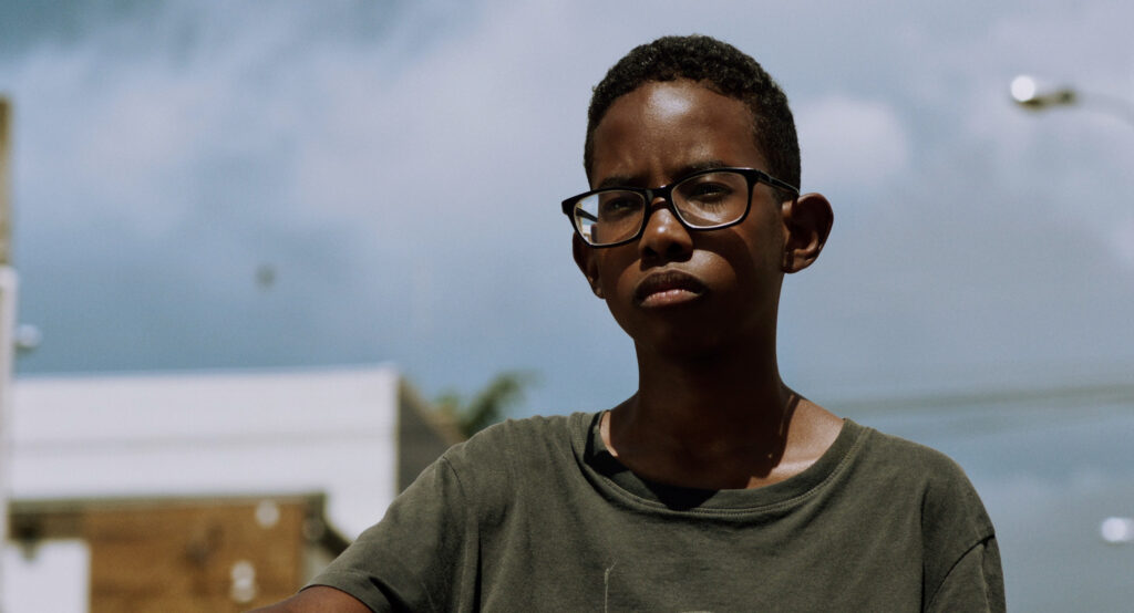 foto de menino negro usando óculos em frente a céu azul