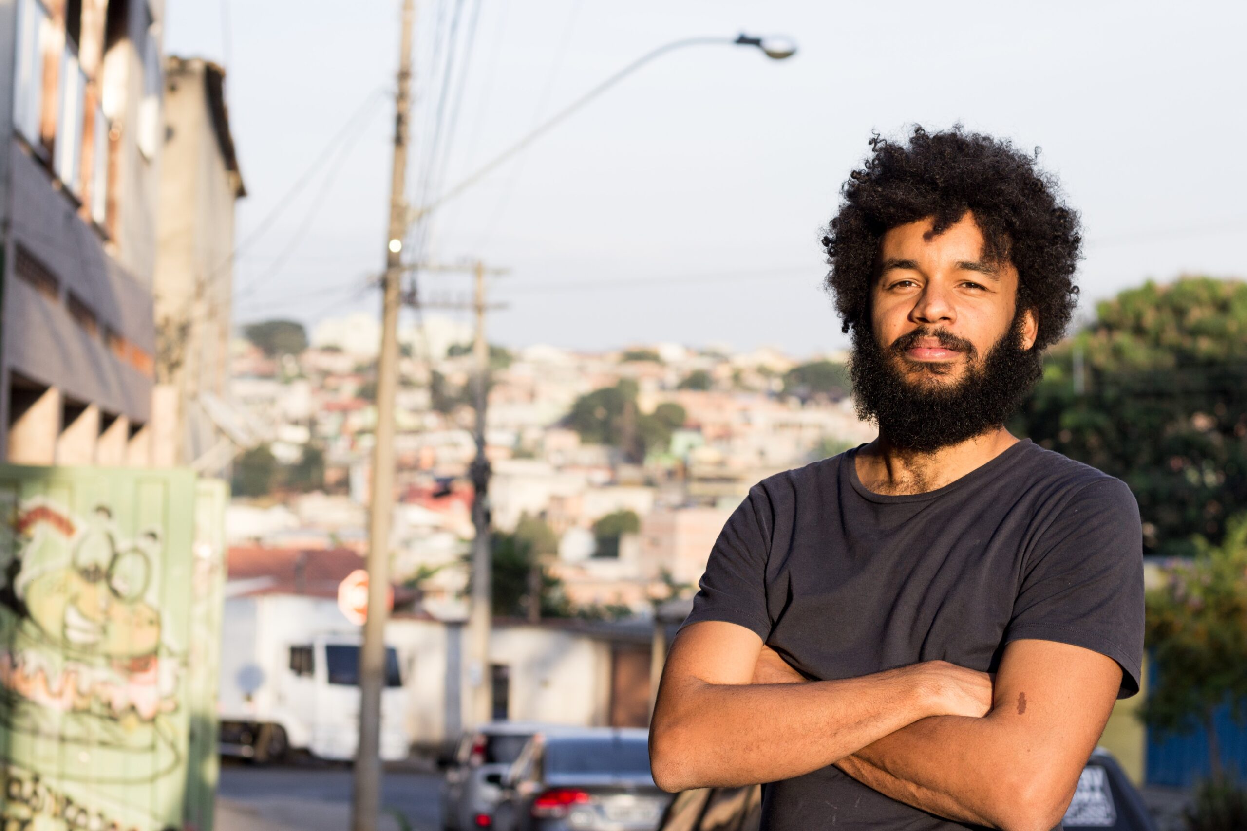 foto de Gabriel Martins, homem negro com cabelo afro em frente a uma favela