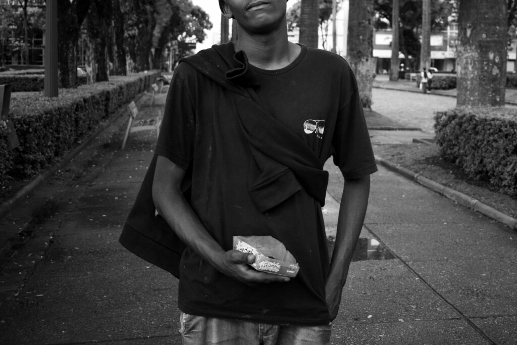 Foto em preto e branco de um jovem negro que segura uma caixa de balas