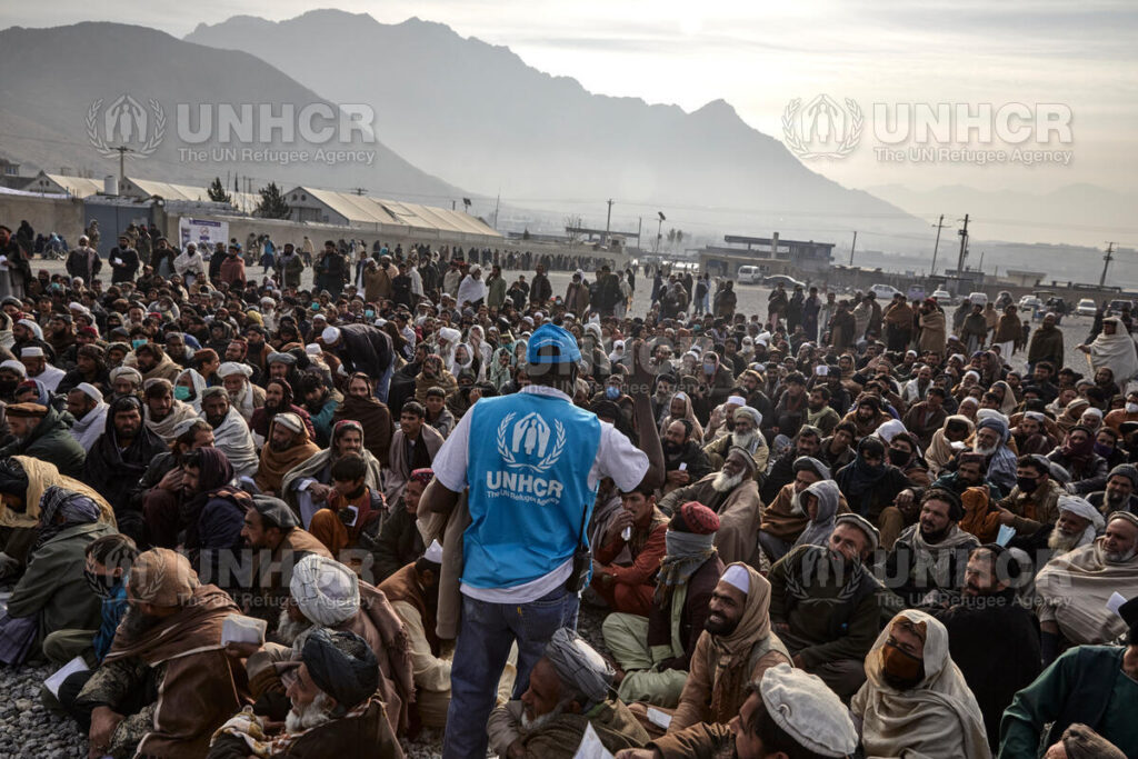 Descrição de imagem: Funcionário da ACNUR ajuda famílias refugiadas esperando o recebimento de auxílio monetário em Kabul.
