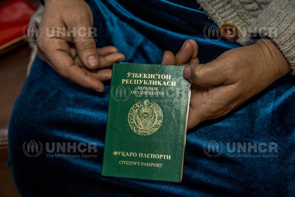 Descrição de imagem: Passaporte verde do Uzbequistão nas mãos de Zukhra Mukanova.
