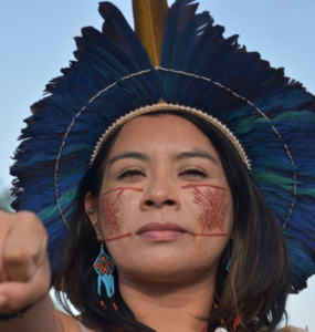 Foto mostra a jornalista e ativista indígena Ariene Susui com pinturas corporais no rosto e um cocar na cabeça