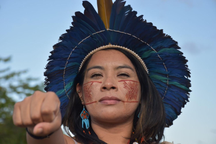 Foto mostra a jornalista e ativista indígena Ariene Susui com pinturas corporais no rosto e um cocar na cabeça