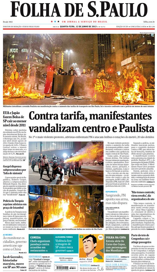 Capa do jornal Folha de São Paulo, dia 12 de junho de 2013. A foto em destaque foi tirada em ambiente aberto, durante a noite, na cidade de São Paulo no momento da manifestação onde um grupo de pessoas estavam próximos de objetos em chamas no chão. O título da página é “Contra tarifa, manifestantes vandalizam centro e Paulista”.