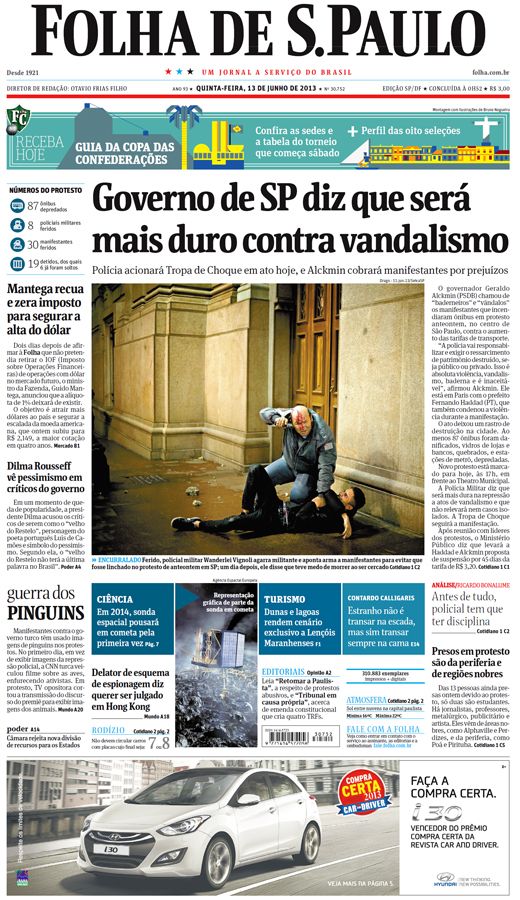 Capa do jornal Folha de São Paulo, dia 13 de junho de 2013. O texto em destaque é “Governo de SP diz que será mais duro contra o vandalismo”, na foto que compõe a capa existem duas pessoas, um policial agachado, fardado, ferido na cabeça, que aponta uma arma para os manifestantes e segurando um manifestante deitado no chão, um homem branco e vestindo roupas pretas, estão em um ambiente aberto na porta de um edifício.