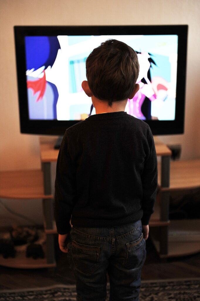imagem na vertical de costas assistindo desenho animado, colorido, na televisão 