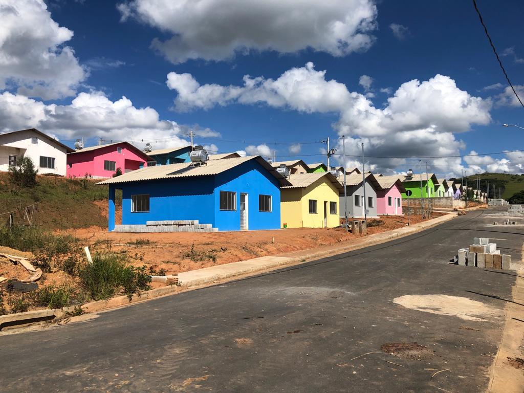 Casas terreas recém construídas, semelhantes umas às outras, com uma porta entre duas janelas nas fachadas. Telhados claros e cada casa é pintada de uma cor diferente: azul, cinza, amarelo, rosa, verde, branca. Há resquícios de construção nas ruas, como blocos de cimento e há um poco de vegetação
