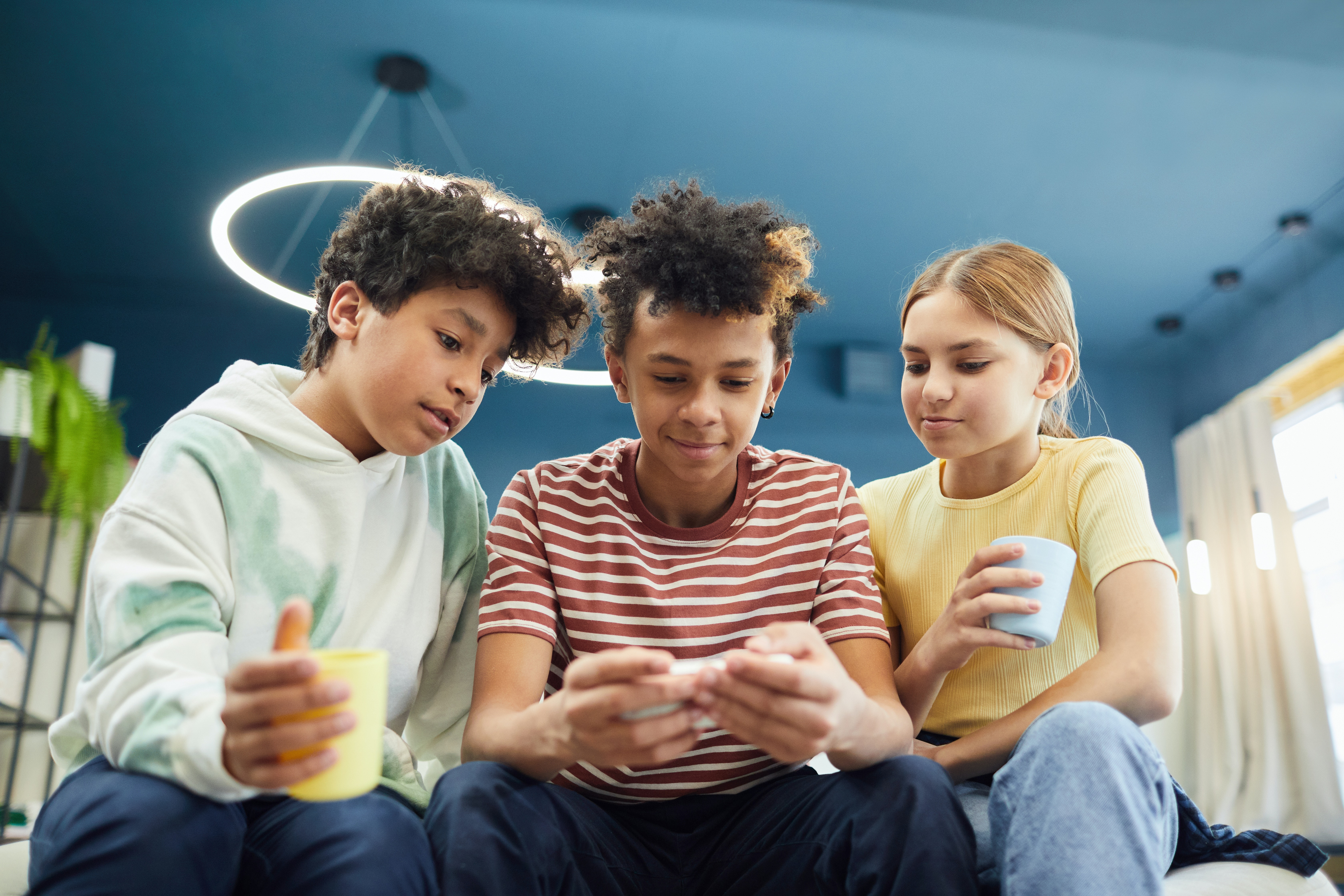 imagem colorida de três crianças usando o celular