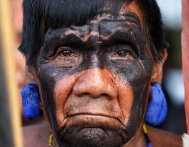 Indígena Yanomami de cabelos pretos e olhos preto, usa ornamento característico da sua cultura na sua orelha e em seu pescoço.