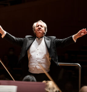 Maestro Fabio Mechetti em uma apresentação frontalmente de braços abertos no meio da imagem