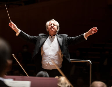 Maestro Fabio Mechetti em uma apresentação frontalmente de braços abertos no meio da imagem