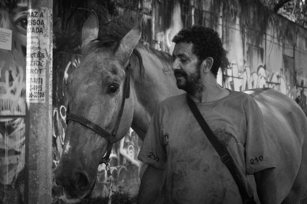 Carroceiro em pé ao lado do seu cavalo em uma rua de Belo Horizonte.