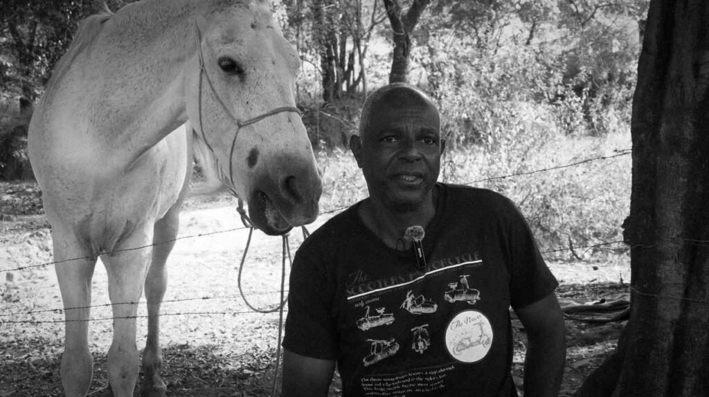 Carroceiro sentado ao lado de um cavalo em seu curral em Belo Horizonte.