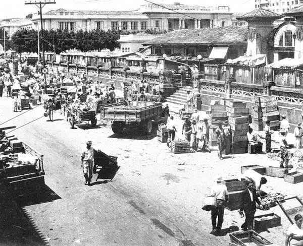 Imagem em preto e branco das ruas de Belo Horizonte cheia de pessoas e carroças, veículos que abasteciam a cidade no século XX.