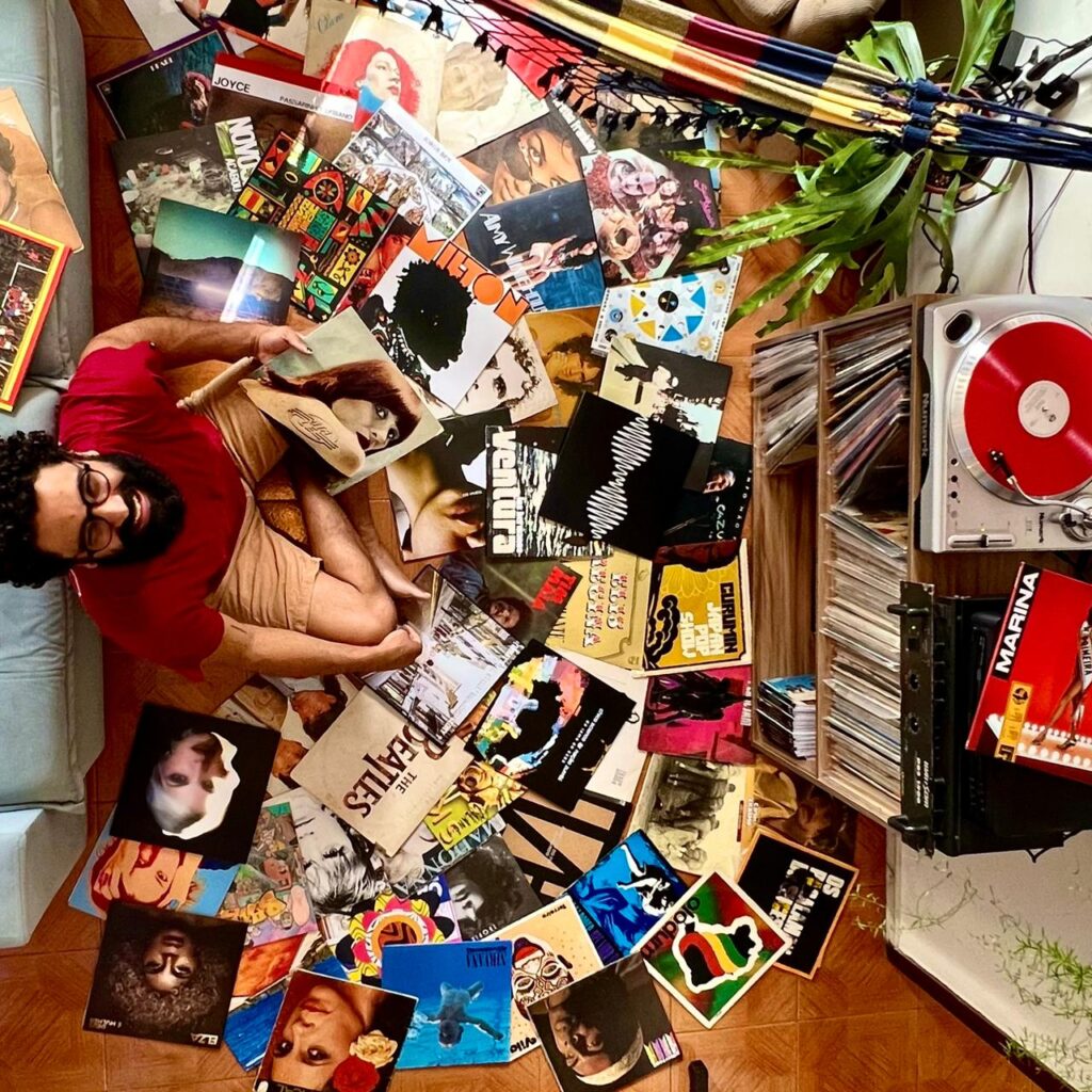 Homem sentado em meio a sua coleção de discos de vinil