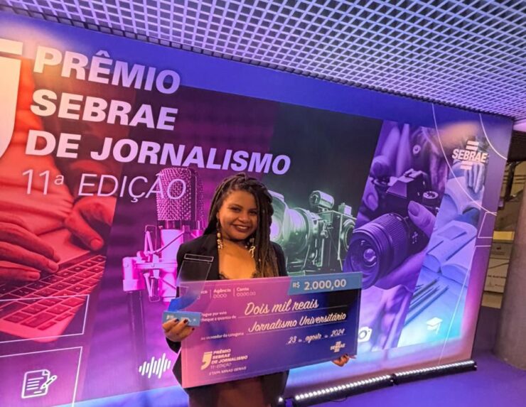 Jovem negra segurando cheque premiado em dois mil reais no evento do Sebrae