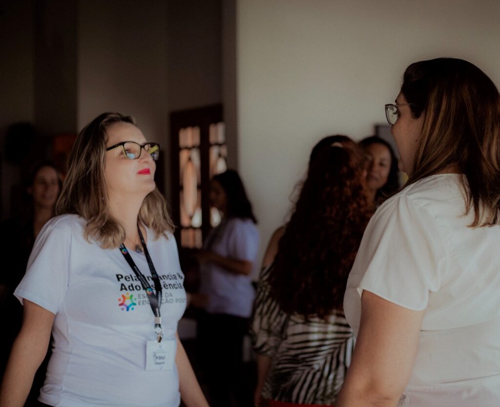 Mulher de óculos e blusa branca em evento de Educação Positiva