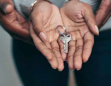 Duas mãos abertas, uma sob a outra, com uma chave de casa dentro