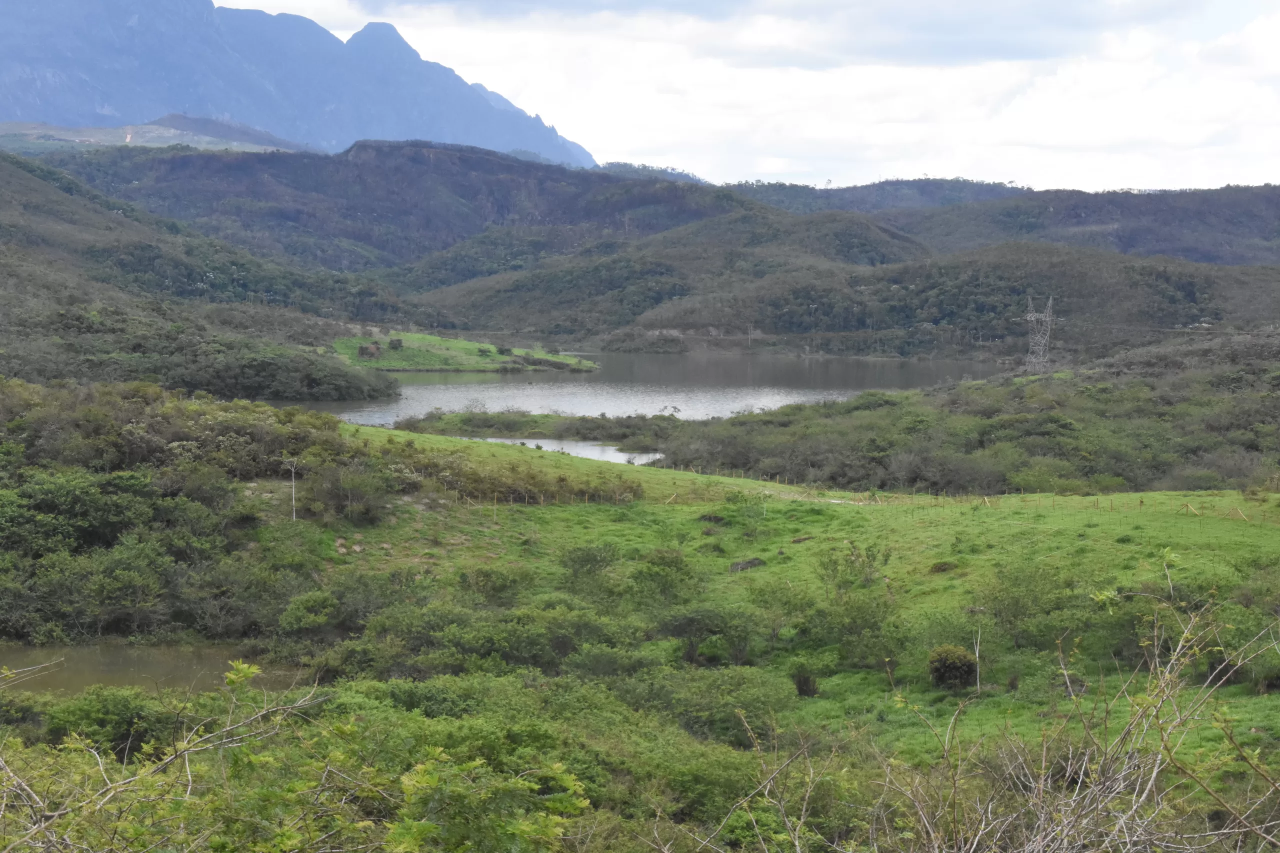 A imagem mostra uma paisagem bonita com muita vegetação, árvores, relevos e um rio grande no centro da imagem.
