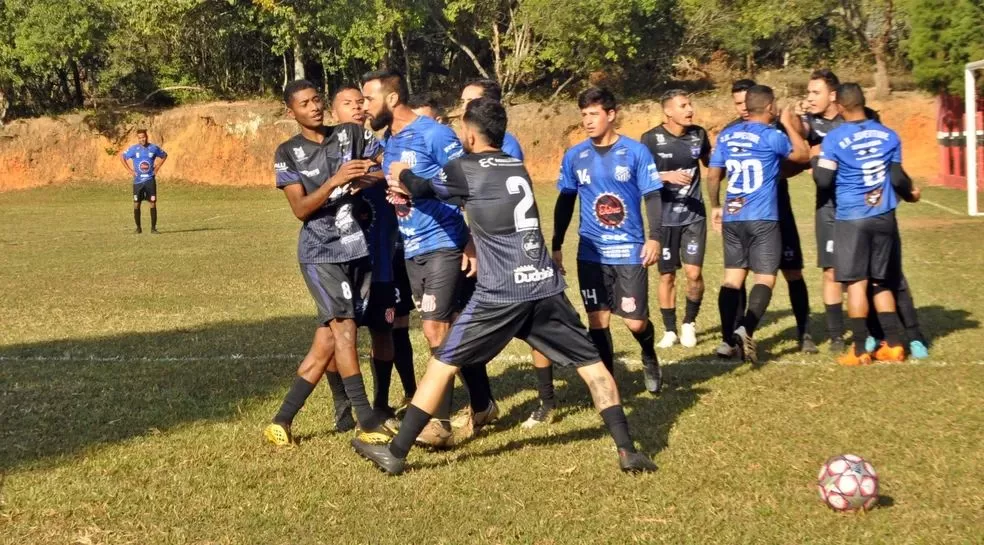 Jogadores de camisa preta e azul em conflito durante uma partida de futebol amador