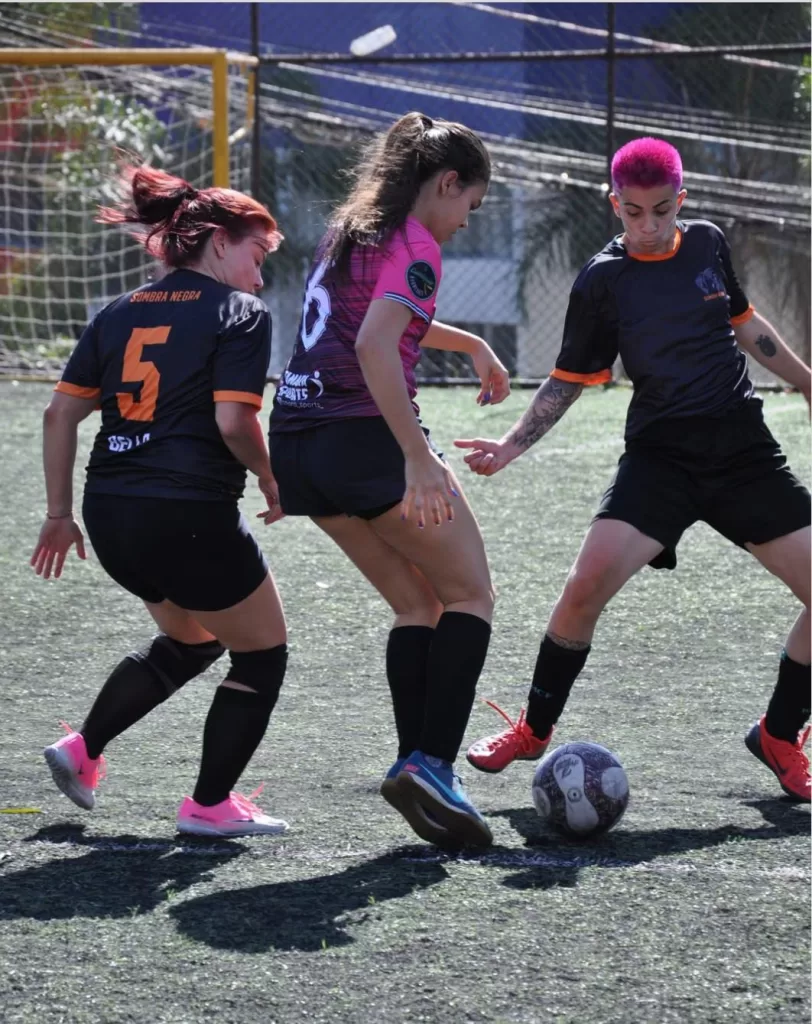 Três mulheres jogando futebol