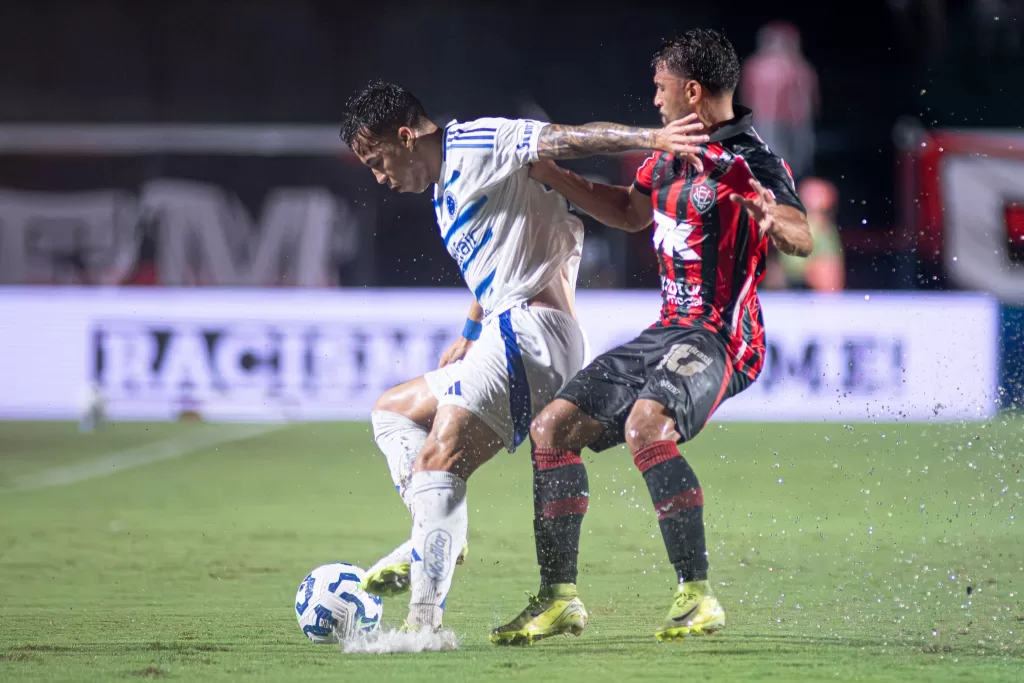 Jogador do vitória em disputa com o jogador do cruzeiro, no gramado cheio de agua