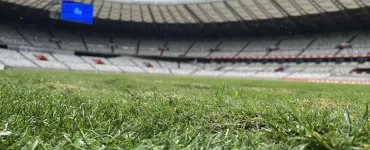 Gramado verde ocupa metade inferior da foto e ao fundo o estádio mineirão e o céu