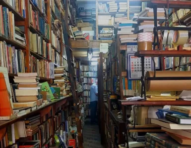 A foto mostra os fundos de uma livraria com prateleiras cheias de livro do chão ao teto.