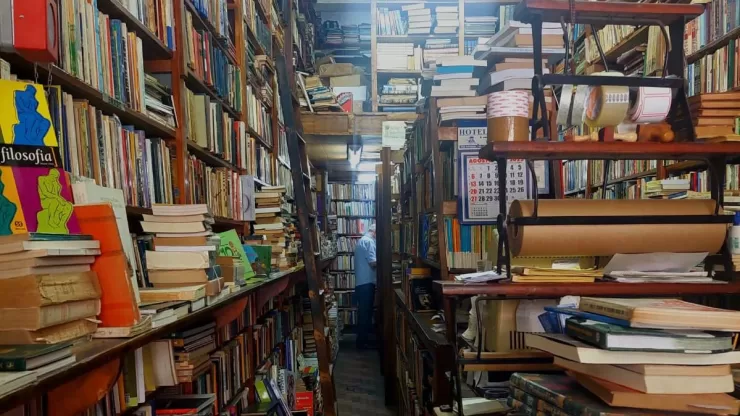 A foto mostra os fundos de uma livraria com prateleiras cheias de livro do chão ao teto.