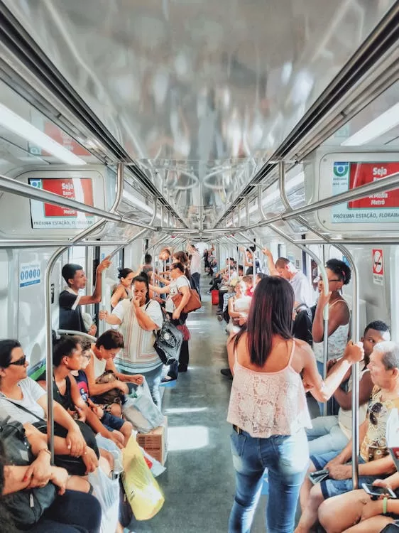 Pessoas dentro de um vagão de metrô no Brasil, sentadas e em pé, demonstrando expressões variadas de cansaço, reflexão e rotina urbana.