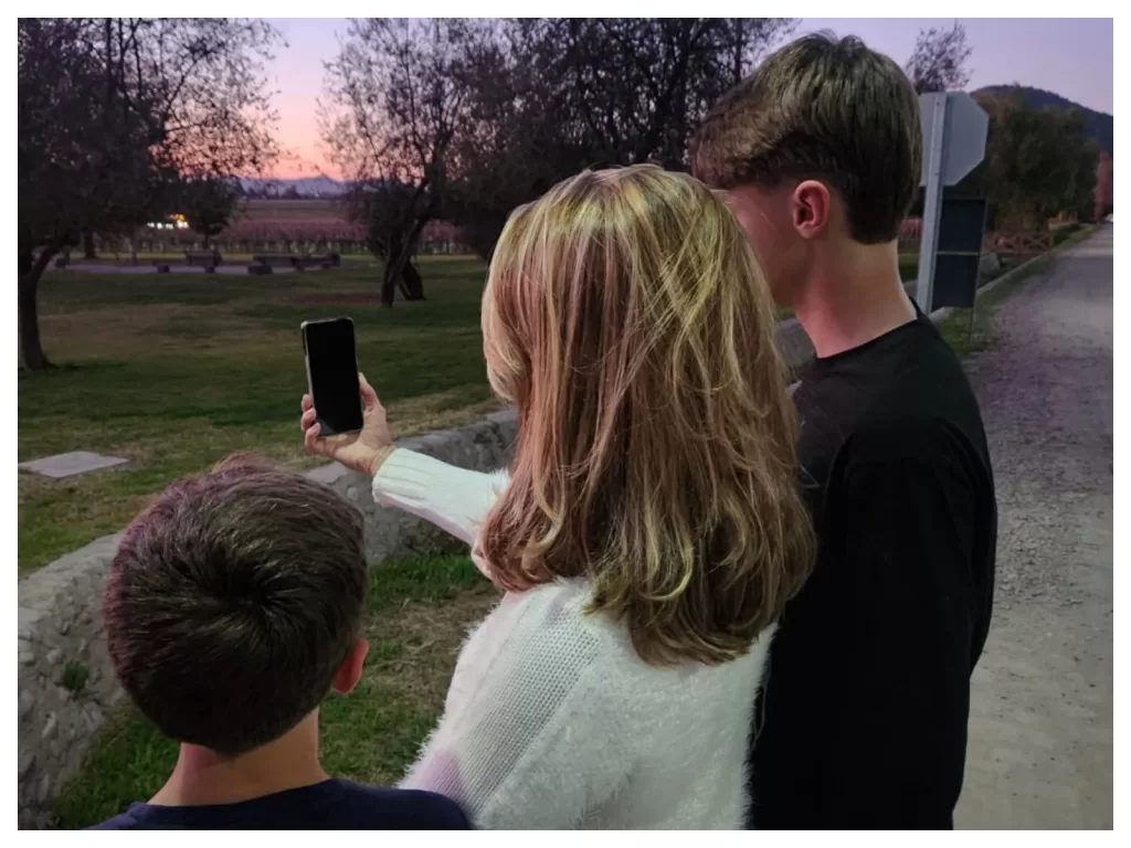 Uma mâe e seus dois filhos olhando para um celular