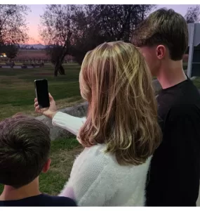 Uma mâe e seus dois filhos olhando para um celular