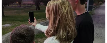 Uma mâe e seus dois filhos olhando para um celular