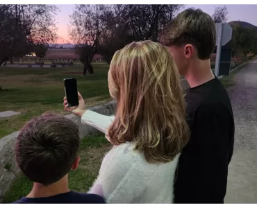 Uma mâe e seus dois filhos olhando para um celular