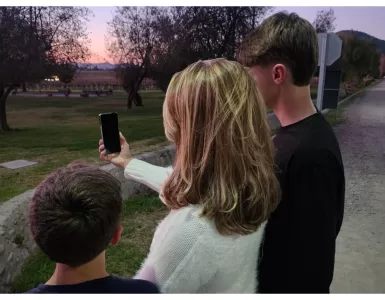 Uma mâe e seus dois filhos olhando para um celular