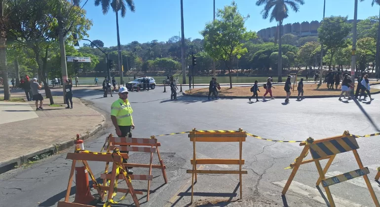 Trânsito intenso na avenida que contorna a Lagoa da Pampulha, em Belo Horizonte, com carros, ônibus e pedestres próximos ao Mineirão.