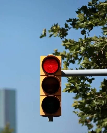 Na imagem, um semáforo vermelho. Ao fundo, um céu azul.
